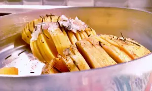 Patate al coppo, tagliate a fisarmonica e condite con erbe aromatiche, pronte per essere cotte.