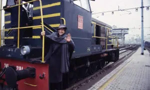 Un uomo sorridente saluta da un treno, come in una delle canzoni milanesi.
