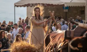 Donna in abito dorato, con spighe di grano che simboleggiano abbondanza e fertilità, durante una festa popolare.