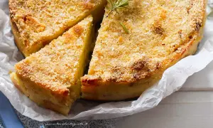 La ricetta del gateau di patate è servita: una torta dorata e croccante, guarnita con rosmarino fresco.