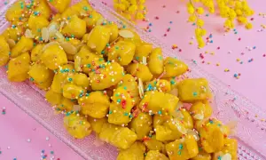 Dolcezza dorata: la ricetta cicerchiata marchigiana, decorata con confettini colorati e mandorle, pronta per essere gustata.