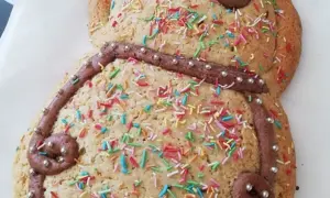 Dolce a forma di pupazzo, decorato con glassa al cioccolato, zuccherini colorati e perline argentate. Una deliziosa ricetta pupa abruzzese pronta da gustare.