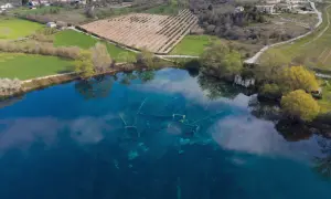 Le rovine sommerse nel lago azzurro evocano un'Atlantide d'Abruzzo. Campi verdi e alberi circondano questo luogo magico.
