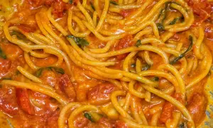 Un primo piatto invitante di linguine allo scarpariello, con pomodorini succosi e basilico fresco in una salsa cremosa.