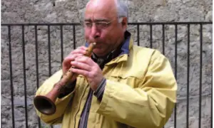 Uomo con occhiali suona uno strumento a fiato, una piva, con un suono melodioso.