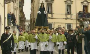 Processione a Sulmona con la Madonna che scappa, portata a spalla da uomini in verde e bianco, mentre i carabinieri sorvegliano.