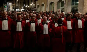 Uomini in toga rossa partecipano alla processione del Venerdì Santo a Sulmona, un momento di profonda spiritualità e tradizione.