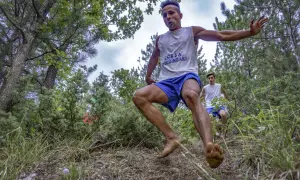 Due giovani atleti corrono a piedi nudi nel bosco, partecipando alla "Corsa degli Zingari". Il primo è in primo piano, in pieno balzo.