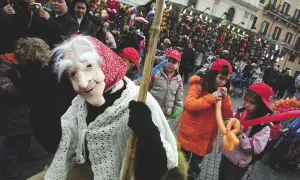 Una maschera della Befana saluta la folla, mentre i bambini giocano con palloncini gonfiabili. Si festeggia la Befana!