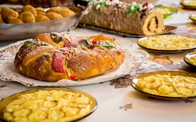 Dolce tipico dell'Epifania: un Roscón de Reyes decorato con frutta candita e mandorle, accompagnato da dolcetti.