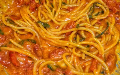 Un primo piatto invitante di linguine allo scarpariello, con pomodorini succosi e basilico fresco in una salsa cremosa.
