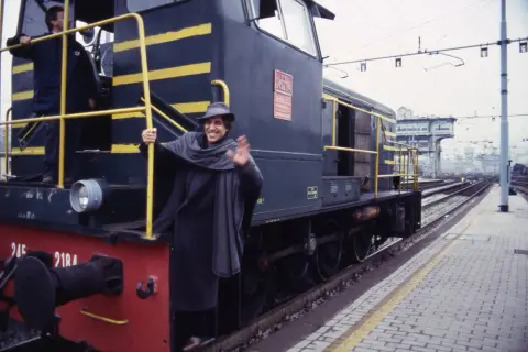 Un uomo sorridente saluta da un treno, come in una delle canzoni milanesi.
