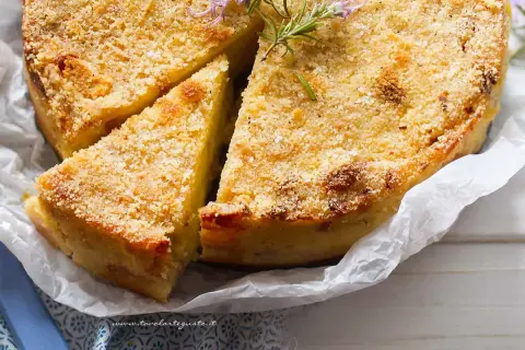 La ricetta del gateau di patate è servita: una torta dorata e croccante, guarnita con rosmarino fresco.