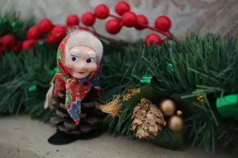 Bambola con scopa su pigna, tra decorazioni natalizie. L'epifania è festivo, un momento magico.