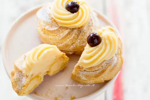Zeppole di San Giuseppe, dolci soffici con crema pasticcera e ciliegina, perfette per la festa del papà. La ricetta delle zeppole di San Giuseppe è un classico.