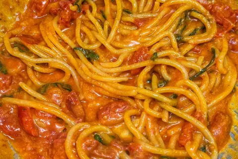 Un primo piatto invitante di linguine allo scarpariello, con pomodorini succosi e basilico fresco in una salsa cremosa.