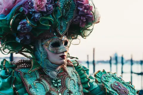 Una maschera veneziana elaborata, con fiori e perle, evoca la storia delle maschere di carnevale.