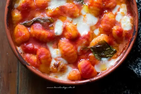 Gnocchi alla napoletana fumanti in terracotta, con pomodoro filante e basilico fresco. Un abbraccio di sapori autentici.