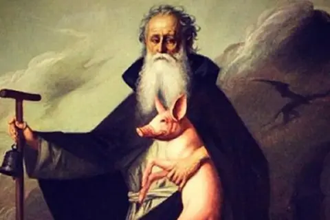 Un anziano barbuto con un maialino rosa, un bastone con campana e un'ombra di drago. La storia del porcellino di Sant'Antonio.