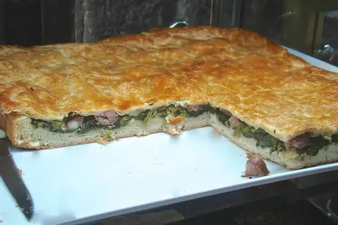 Pizza ripiena salsiccia e friarielli, un classico napoletano dal sapore intenso. La pasta dorata racchiude un cuore verde e saporito.