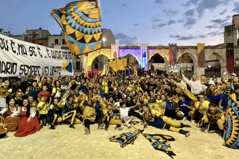 Folla festante in costume, bandiere sventolano, un'atmosfera di festa per la giostra cavalleresca Sulmona.