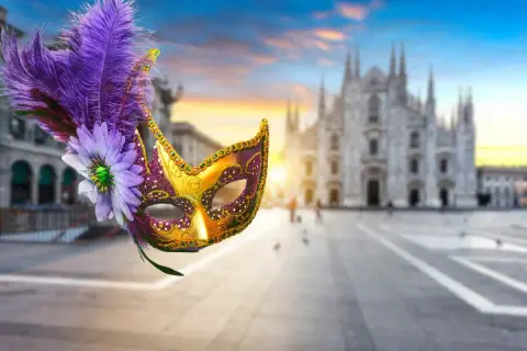 Maschere milanesi decorate con piume e fiori, con il Duomo di Milano sullo sfondo al tramonto.