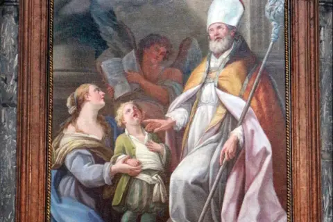 San Biagio, con mitra e pastorale, benedice un bambino. Il nome Biagio evoca protezione e guarigione.