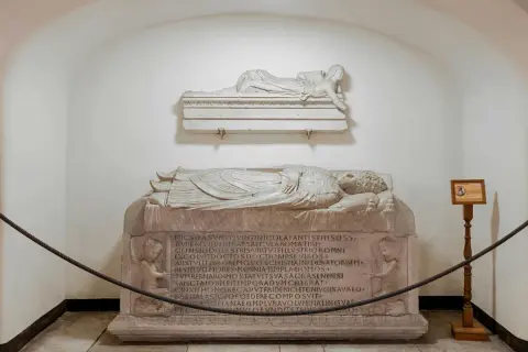 Sarcofagi scolpiti, uno con angeli, che illustrano il necropoli significato. Un'antica tomba con iscrizioni latine.