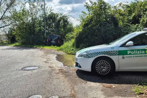 Sei di Paderno Dugnano se vedi la Polizia locale vicino a un'auto nera parcheggiata male e una pozzanghera sull'asfalto.