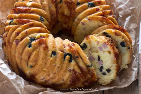 Una golosa ciambella salata napoletana, ricca di olive nere e cubetti di prosciutto, pronta per essere gustata.