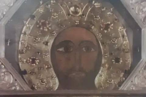 Volto del Cristo Acheropita, icona bizantina con aureola decorata da gemme e ricami dorati, incastonata in una cornice argentata.