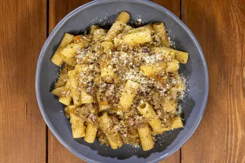 Piatto di pasta con sugo ricco e formaggio grattugiato, una deliziosa finta genovese napoletana.