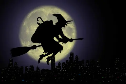La Befana vola su una scopa contro la luna piena, sopra una città illuminata. Viva viva la Befana!