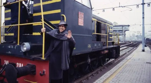 Un uomo sorridente saluta da un treno, come in una delle canzoni milanesi.