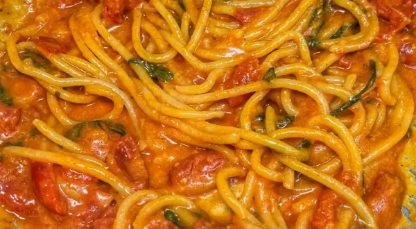 Un primo piatto invitante di linguine allo scarpariello, con pomodorini succosi e basilico fresco in una salsa cremosa.