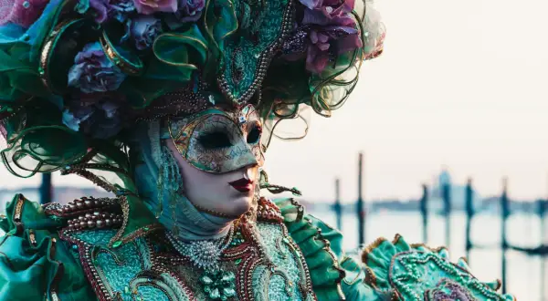 Una maschera veneziana elaborata, con fiori e perle, evoca la storia delle maschere di carnevale.