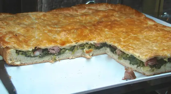Pizza ripiena salsiccia e friarielli, un classico napoletano dal sapore intenso. La pasta dorata racchiude un cuore verde e saporito.