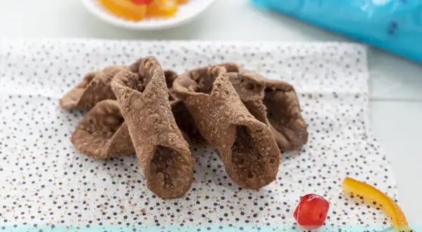 Scorza cannoli siciliani ricetta originale: croccanti involucri pronti per essere farciti, con canditi e ciliegina a lato.