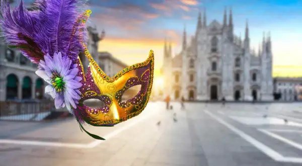 Maschere milanesi decorate con piume e fiori, con il Duomo di Milano sullo sfondo al tramonto.