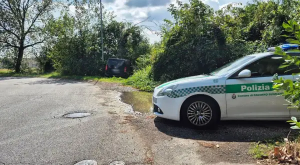 Sei di Paderno Dugnano se vedi la Polizia locale vicino a un'auto nera parcheggiata male e una pozzanghera sull'asfalto.