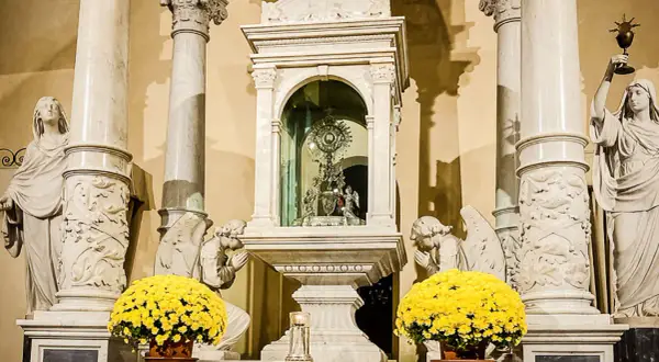 Altare con ostensorio scintillante, angeli adoranti e fiori gialli, evocando un miracolo eucaristico.