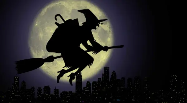La Befana vola su una scopa contro la luna piena, sopra una città illuminata. Viva viva la Befana!