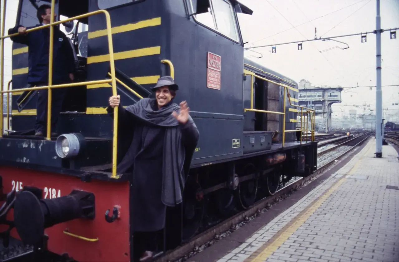 Un uomo sorridente saluta da un treno, come in una delle canzoni milanesi.