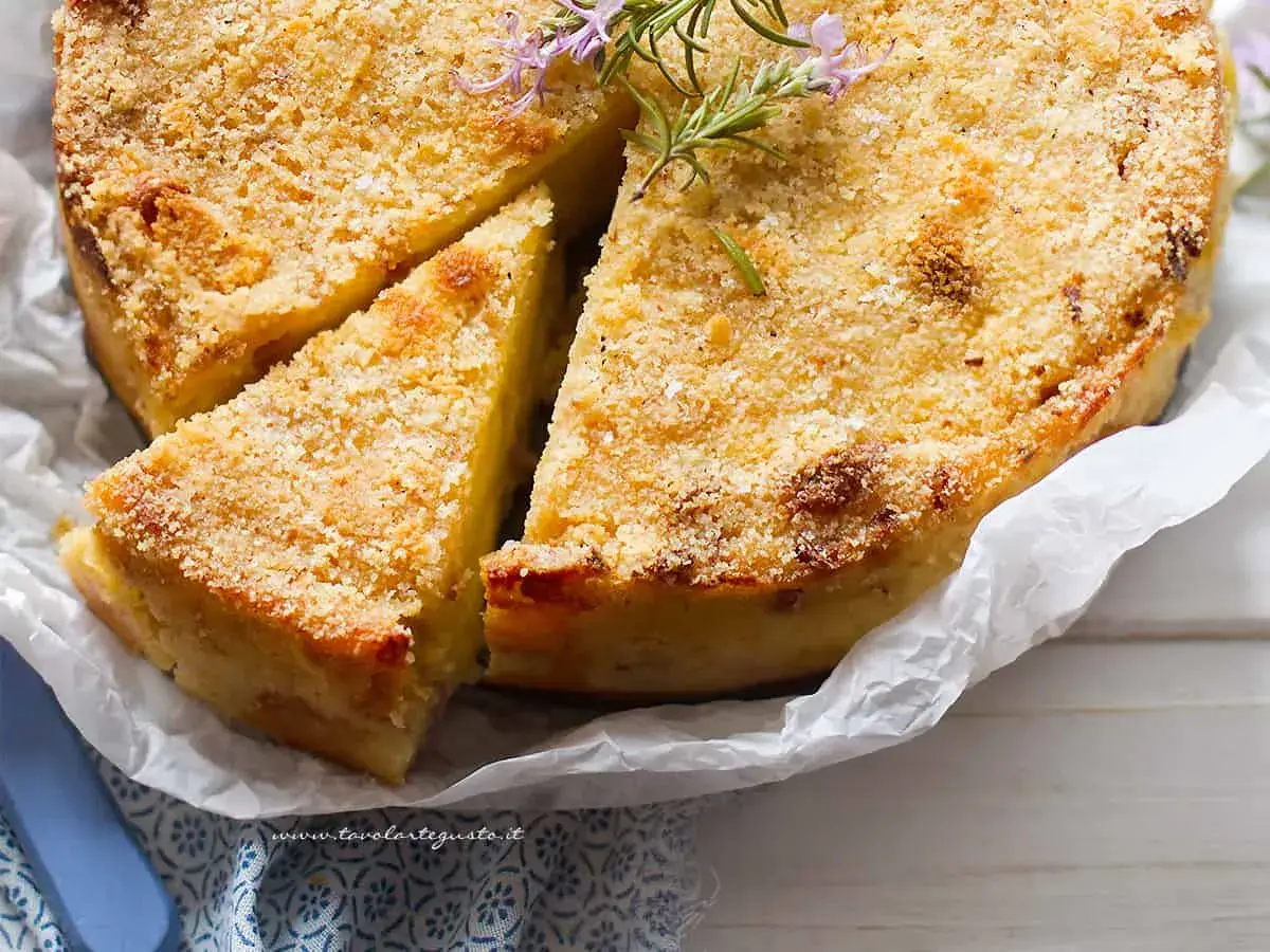 La ricetta del gateau di patate è servita: una torta dorata e croccante, guarnita con rosmarino fresco.