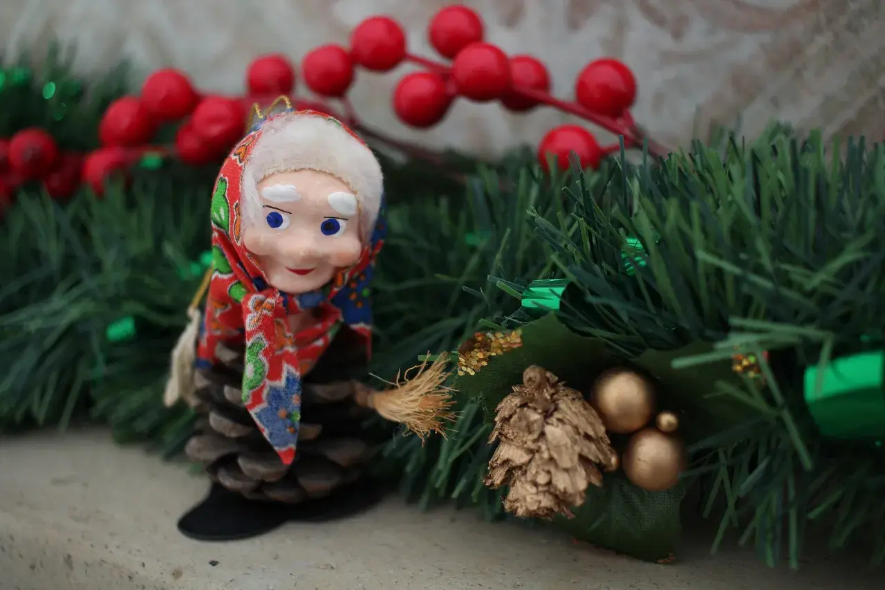 Bambola con scopa su pigna, tra decorazioni natalizie. L'epifania è festivo, un momento magico.