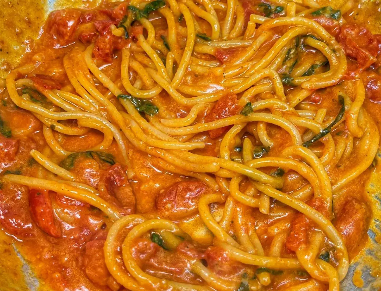 Un primo piatto invitante di linguine allo scarpariello, con pomodorini succosi e basilico fresco in una salsa cremosa.