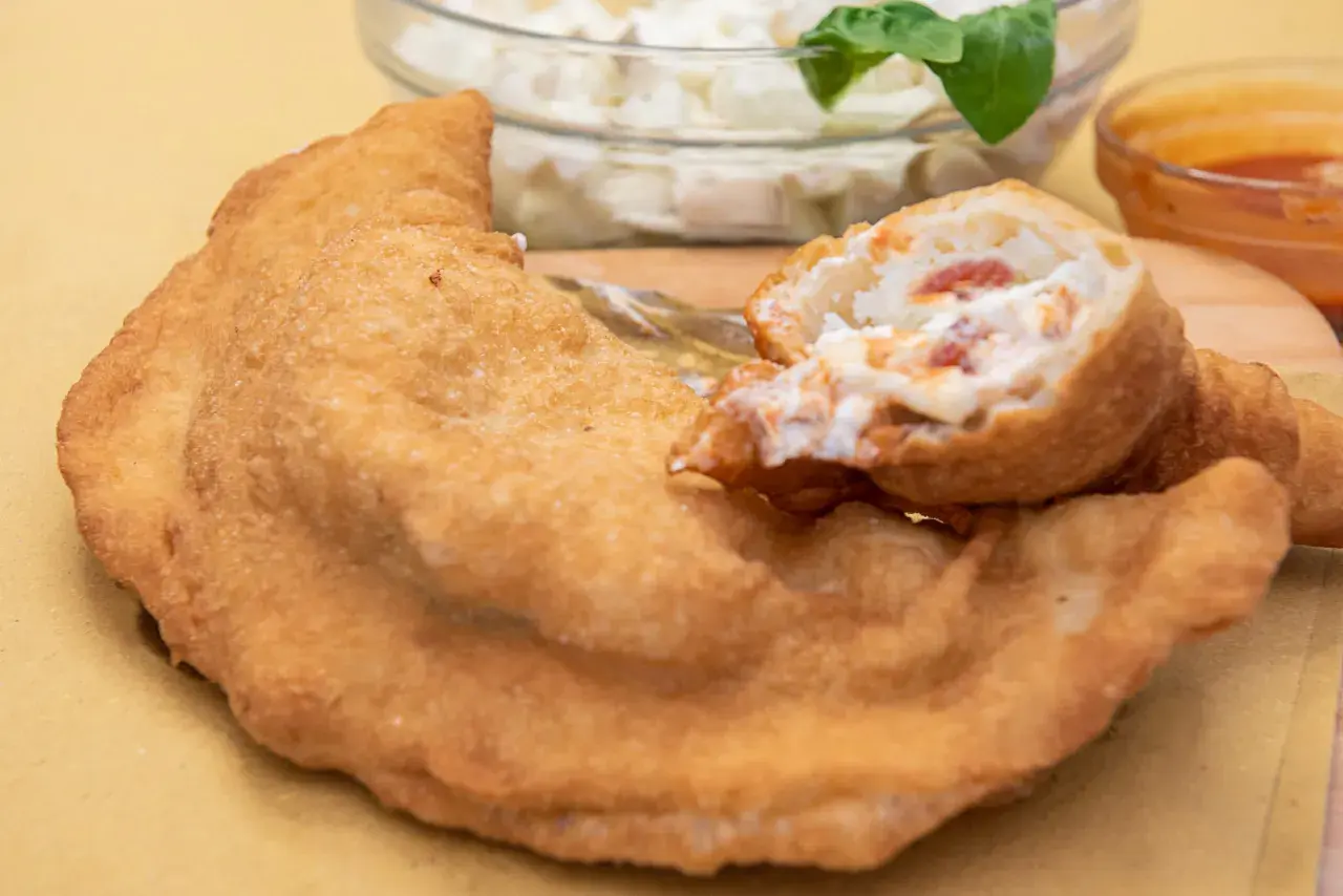 Pizza fritta napoletana: impasto dorato e ripieno cremoso con pomodoro e mozzarella. Ingredienti semplici per un gusto unico.