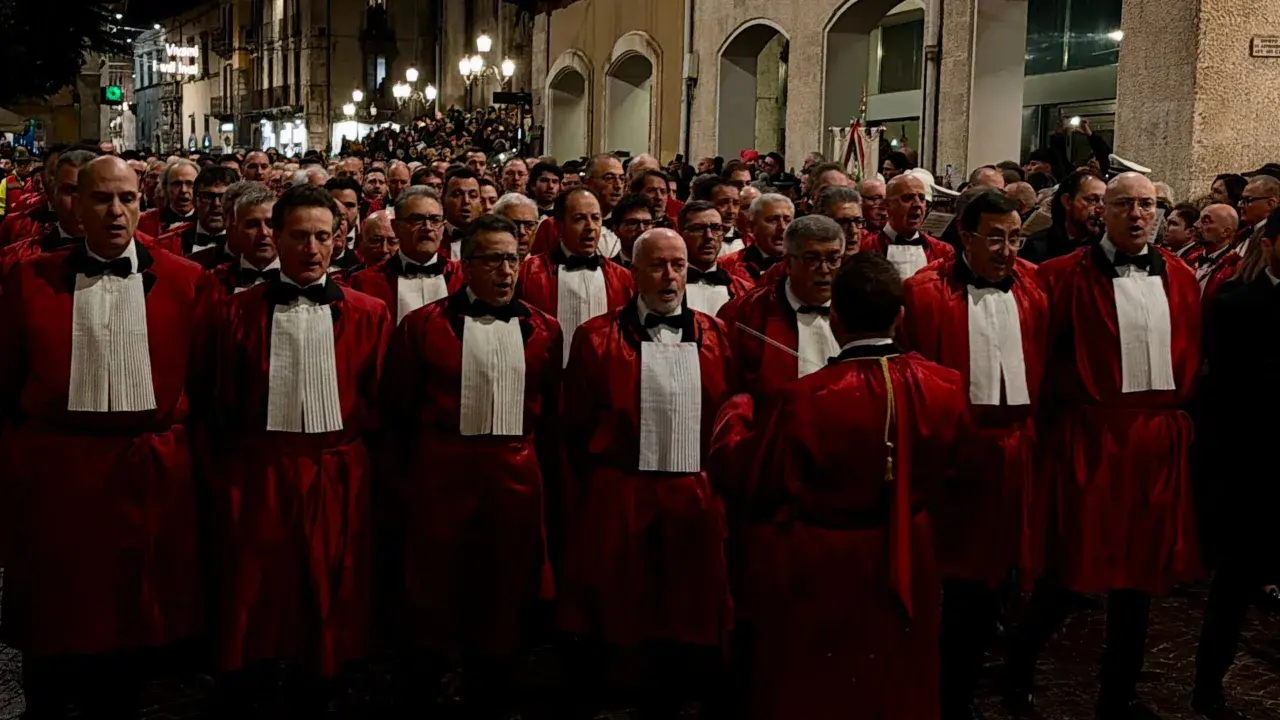 Uomini in toga rossa partecipano alla processione del Venerdì Santo a Sulmona, un momento di profonda spiritualità e tradizione.
