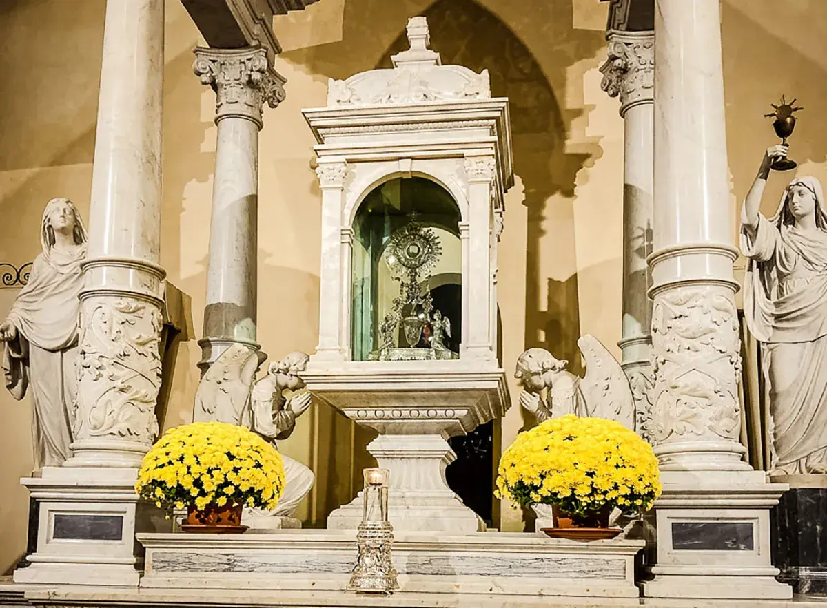 Altare con ostensorio scintillante, angeli adoranti e fiori gialli, evocando un miracolo eucaristico.