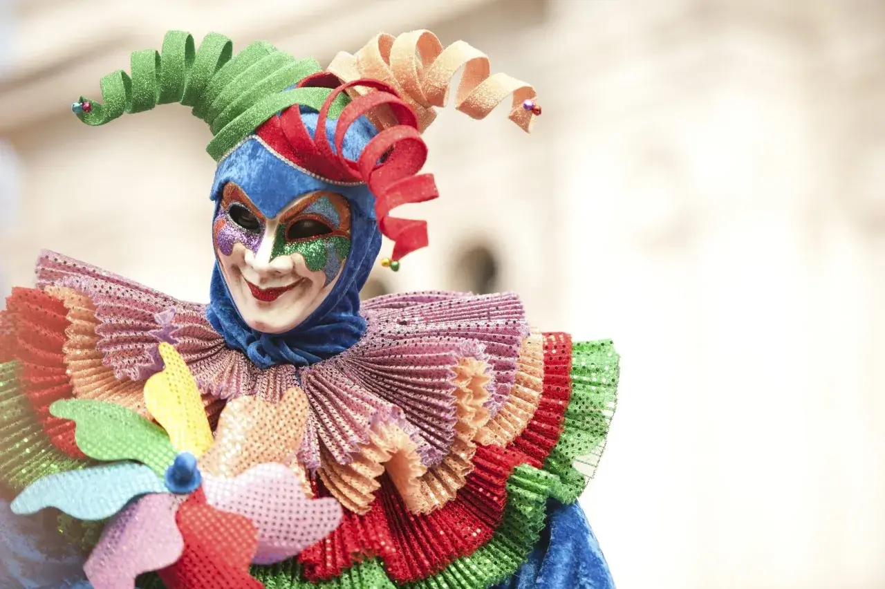 Maschera colorata con cappello a spirale, un costume da giullare che evoca la gioia del carnevale, una festa pagana di travestimenti e allegria.
